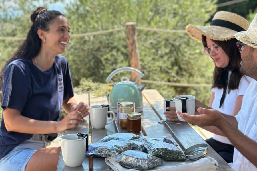 A woman drinking tea at a table overlooking the Ikarian sea